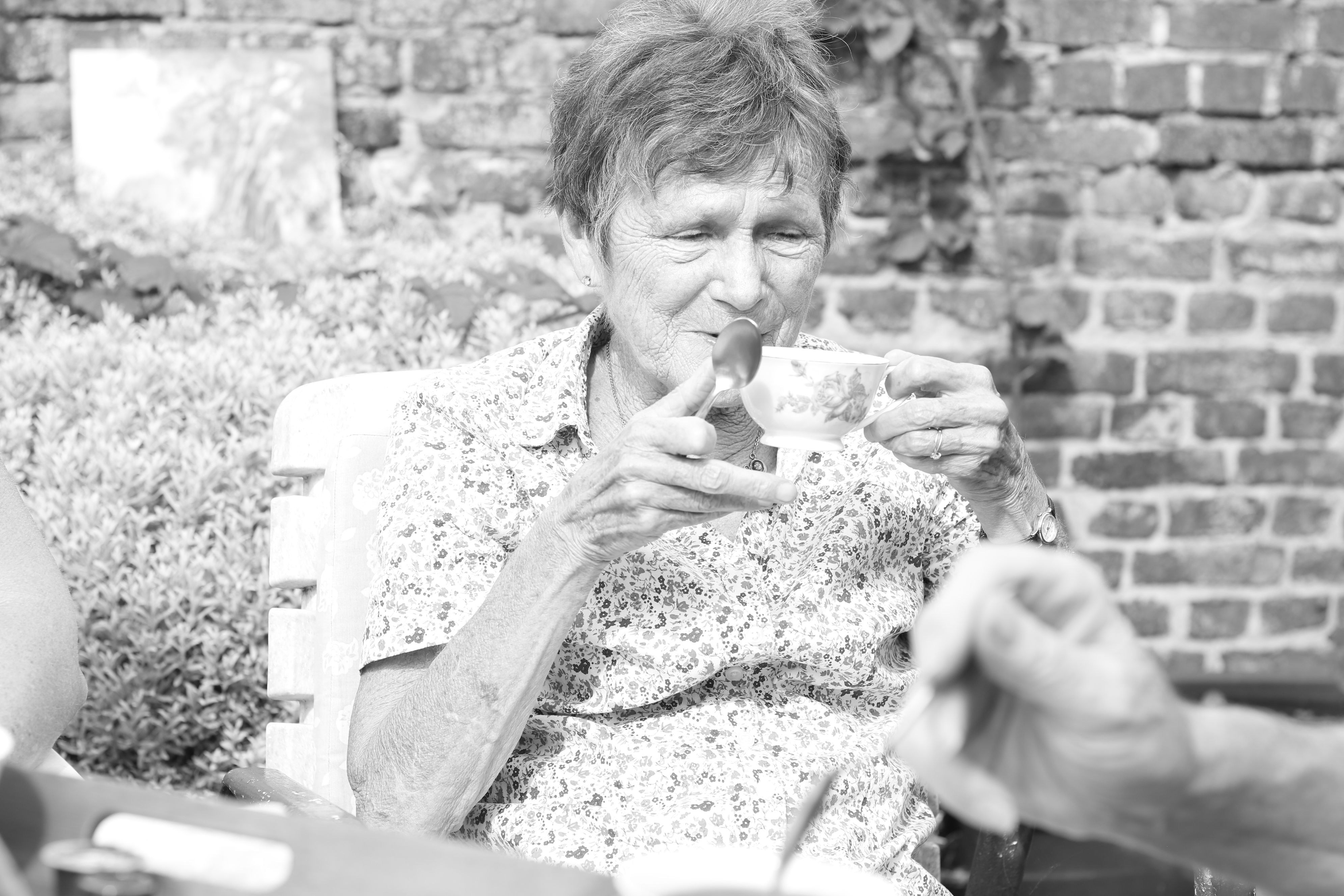 Photo en noir et blanc d'une dame âgée avec une tasse de café en porcelaine en main. ©Armelle Delmelle